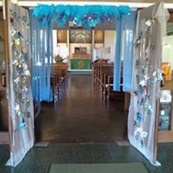 Picture showing the open doors of the church decorated with blue crepe paper