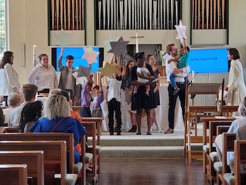 Children welcoming Baby at their baptism by holding up stars